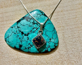 May include: A silver chain necklace with a square pendant featuring a dark iridescent opal stone.