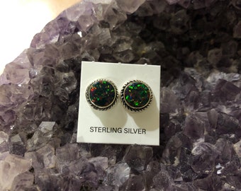 May include: A pair of sterling silver earrings with round, iridescent opal stones. The earrings are displayed on a white card with the text "STERLING SILVER".