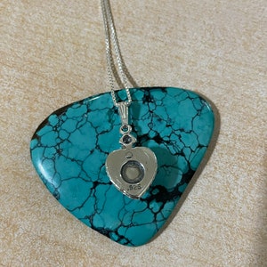 May include: A silver heart-shaped pendant necklace with a small clear stone in the center. The back of the pendant is stamped with ".925".