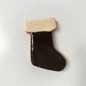 May include: A ceramic Christmas stocking ornament with a white top and a black body.