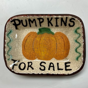 May include: A rectangular ceramic tray with a cream-colored crackle glaze finish. The center features a painted orange pumpkin with a green stem. The text PUMPKINS is printed above the pumpkin and FOR SALE is printed below in black lettering.