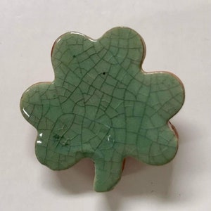 May include: A green ceramic shamrock with a crackled glaze. The shamrock is a traditional Irish symbol of good luck.