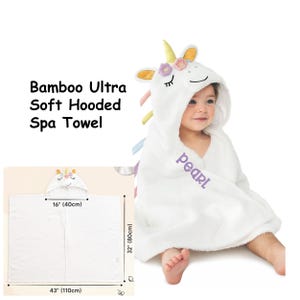 May include: White hooded towel with a unicorn design. The towel is made of bamboo and is ultra soft. The towel is 43 inches wide and 32 inches tall. The hood is 16 inches wide. The towel has the word "pearl" embroidered on it.