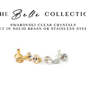 May include: The Belle Collection: Swarovski clear crystals set in solid brass or stainless steel.  Gold and silver-toned metal settings showcase sparkling clear crystals.  Each setting features a small, round crystal. The image shows two pairs of these crystal embellishments, one gold and one silver.