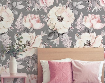 Puede incluir: Un dormitorio con un papel tapiz floral gris con flores rosas y blancas. La cama tiene una manta rosa y dos almohadas rosas. Una mesita de noche rosa con un jarrón y libros está al lado de la cama.