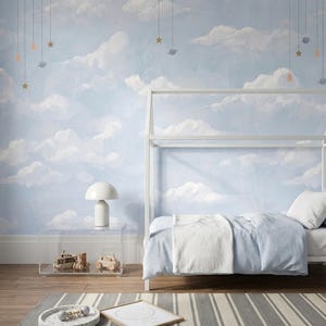 Könnte beinhalten: Ein Schlafzimmer mit hellblauer Tapete, bemalten weißen Wolken und hängenden Himmelskörpern. Ein weißes Hausbett mit hellblauer Bettwäsche, ein Beistelltisch aus klarem Acryl mit einer weißen Lampe und ein gestreifter Teppich sind zu sehen.