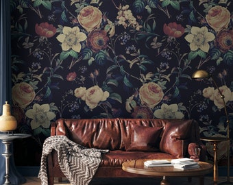 May include: A room featuring a dark floral wallpaper with large roses in cream, yellow, and red hues. A brown leather sofa with a throw blanket sits in front of the wall. A round wooden coffee table and a side table with a lamp are also present.