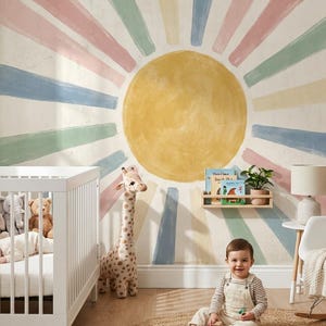 May include: A nursery with a white crib, a baby, and a smiling toddler playing with blocks on a round jute rug. The wall features a painted sun design with pastel rays. A giraffe plush toy stands nearby.
