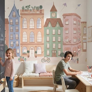 以下が含まれることがあります： 街をテーマにした壁画のある子供部屋。左側にはチョークの絵が描かれた黒板があります。女の子が黒板に絵を描いています。男の子は机に座って絵を描いています。丸いジュートラグが床にあります。