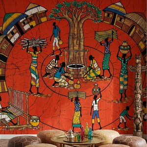 May include: A vibrant room featuring a large, red wall tapestry with an African village scene. The room includes several brown leather ottomans, a round brass coffee table, and a patterned rug. Decorative woven wall hangings and a wooden totem pole add to the decor.