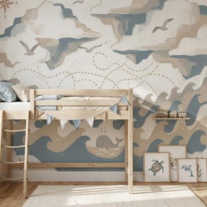 May include: A nautical-themed bedroom with a light wood loft bed, a white rug, and a wall mural depicting clouds, waves, and a compass rose. The mural features a whale, seagulls, and framed art prints. A small shelf holds toy trains.