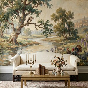May include: A living room scene featuring a cream-colored sofa, a wooden coffee table, and a patterned rug. The backdrop is a large mural depicting a serene landscape with trees, a river, and birds. A brass candelabra and a vase of flowers are on the table.