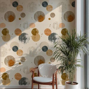 Pode incluir: Interior de uma sala com uma parede estampada com círculos sobrepostos em cinza, laranja e verde oliva. Uma cadeira de madeira com assento branco está em frente à parede. Uma planta em vaso está à direita. O chão é de madeira.
