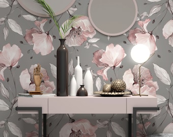 Puede incluir: Un papel tapiz floral rosa y gris con una consola rosa y patas de metal negro. La mesa está decorada con una escultura de mano de madera, un jarrón con una rama frondosa y varios artículos decorativos blancos y dorados.