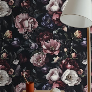 Könnte beinhalten: Dunkle Blumen Tapete mit großen Pfingstrosen in Rosa, Burgunderrot und Weiß vor schwarzem Hintergrund. Ein hölzerner Beistelltisch mit einem Zahnbürstenhalter, Seife und einer Muschel. Ein weißer Lampenschirm ist sichtbar.