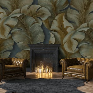 Könnte beinhalten: Ein Wohnzimmer mit zwei braunen Chesterfield-Ledersesseln, einem dunkelgrauen Teppich und einem Kamin. Die Wand ist mit einer großformatigen botanischen Tapete in Grün- und Goldtönen geschmückt. Eine goldene Stehlampe sorgt für Ambiente.