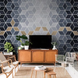 May include: A living room interior with a geometric patterned wallpaper in shades of blue and gold. A mid-century modern style wooden cabinet with a television on top sits in front of the wall. Two chairs and a coffee table with books are in the foreground.