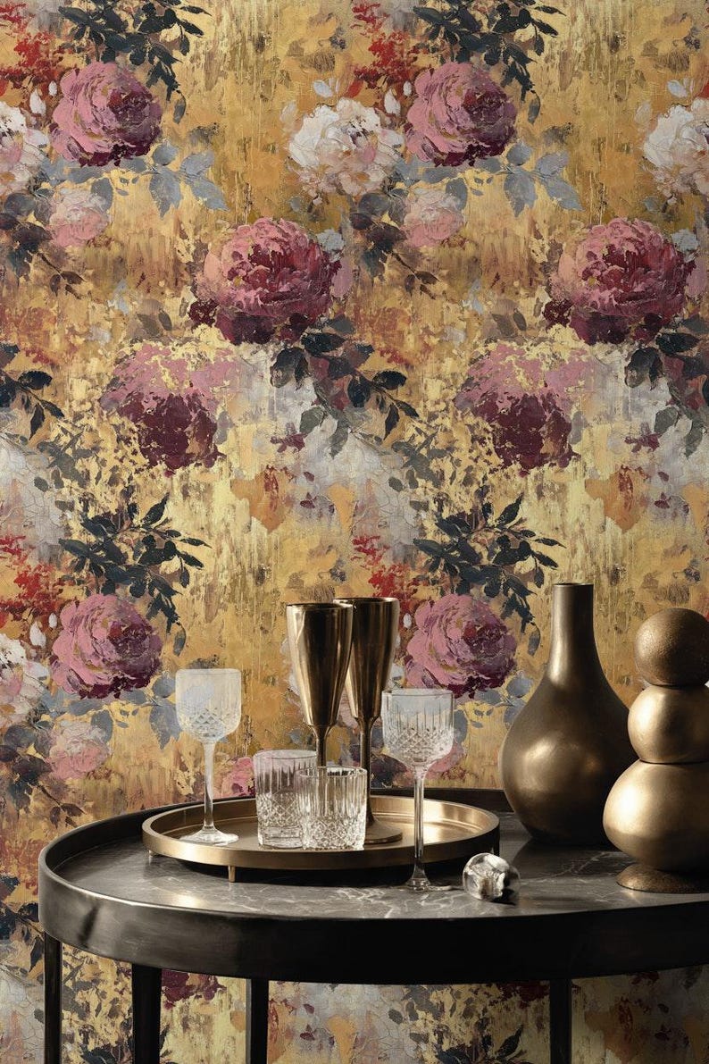 May include: An artistic display with a floral wallpaper backdrop featuring large roses in pink, burgundy, and white. A round table holds glassware, gold-toned vases, and a serving tray. The overall aesthetic is elegant and artistic.