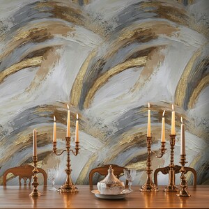 Pode incluir: Uma cena de sala de jantar com uma longa mesa de madeira adornada com casti&ccedil;ais dourados com velas acesas. O fundo &eacute; uma parede texturizada com um design abstrato em ouro, branco e cinza. Cadeiras circundam a mesa, criando um ambiente elegante.