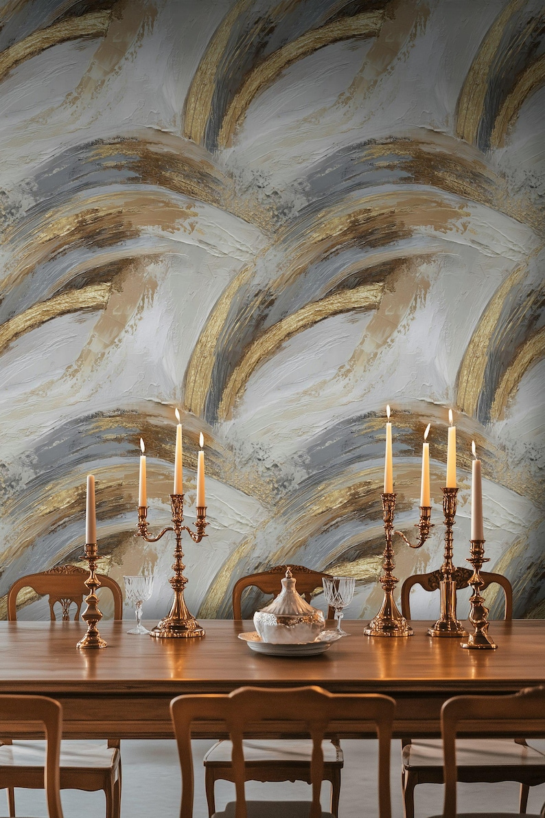Pode incluir: Uma cena de sala de jantar com uma longa mesa de madeira adornada com casti&ccedil;ais dourados com velas acesas. O fundo &eacute; uma parede texturizada com um design abstrato em ouro, branco e cinza. Cadeiras circundam a mesa, criando um ambiente elegante.