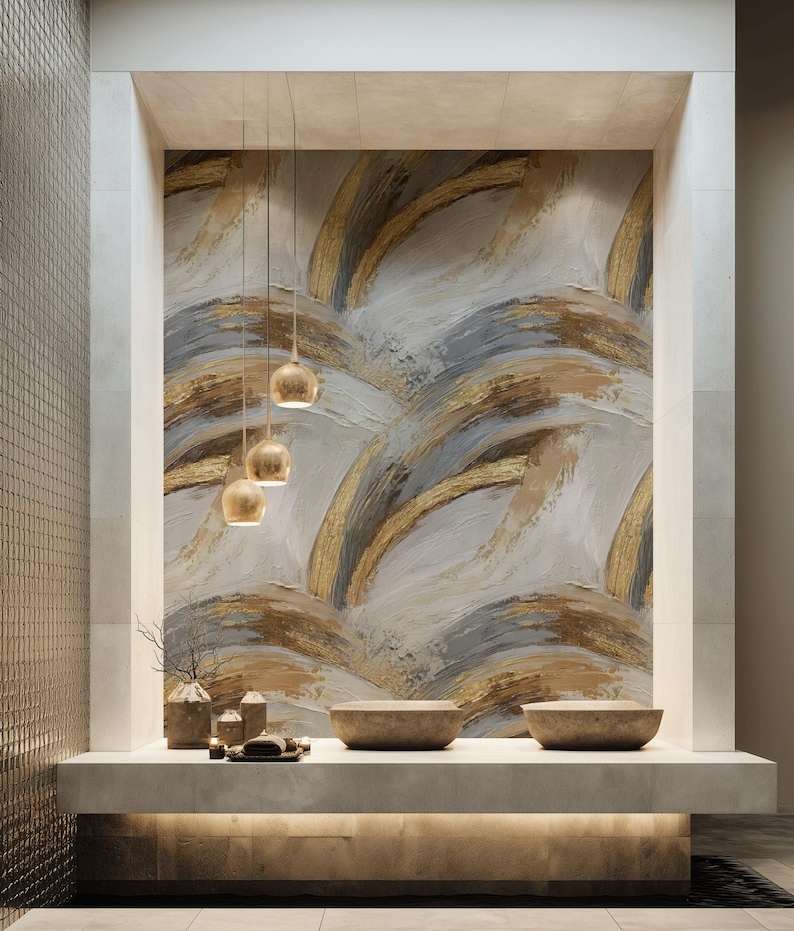 Pode incluir: Design moderno de casa de banho com uma parede texturizada com pinceladas abstratas douradas, cinzentas e brancas. O espa&ccedil;o inclui uma bancada de pedra com duas pias, itens decorativos e lumin&aacute;rias penduradas com tons dourados.