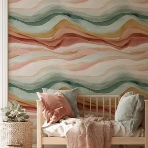 May include: A bedroom scene featuring a light wood daybed with pillows and a blanket. The wall behind the bed is decorated with a watercolor-style mural in shades of pink, green, and yellow. A woven basket with a plant sits to the left.