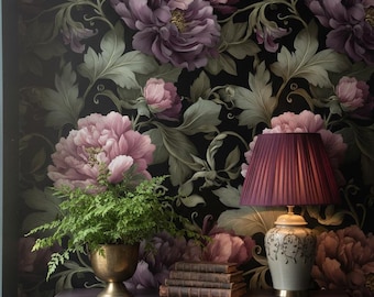 May include: A dark purple table with a lamp, books, and a potted plant in front of a floral wallpaper. The lamp has a pleated shade and a decorative base. The wallpaper features large, pink and purple flowers.