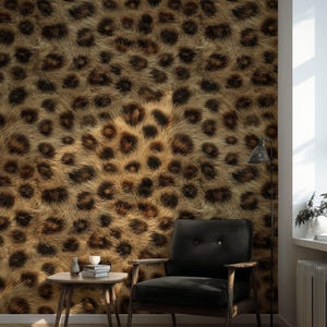 May include: A room with a leopard print wallpaper feature wall. A black armchair with wooden arms and legs is positioned in front of the wall. A small wooden side table holds books and a vase. A floor lamp stands nearby.