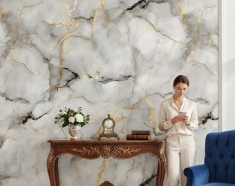 Puede incluir: Una pared con efecto mármol con vetas doradas es el telón de fondo de una habitación. Se ve una consola de madera, un sillón de terciopelo azul y una mujer vestida de crema. Un jarrón con flores blancas y un reloj pequeño están sobre la mesa.