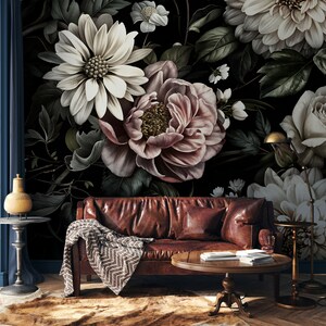 Puede incluir: Un sof&aacute; de cuero marr&oacute;n oscuro con una manta y una mesa de caf&eacute; delante. La pared detr&aacute;s del sof&aacute; est&aacute; cubierta con un papel tapiz floral con grandes flores blancas y rosas.