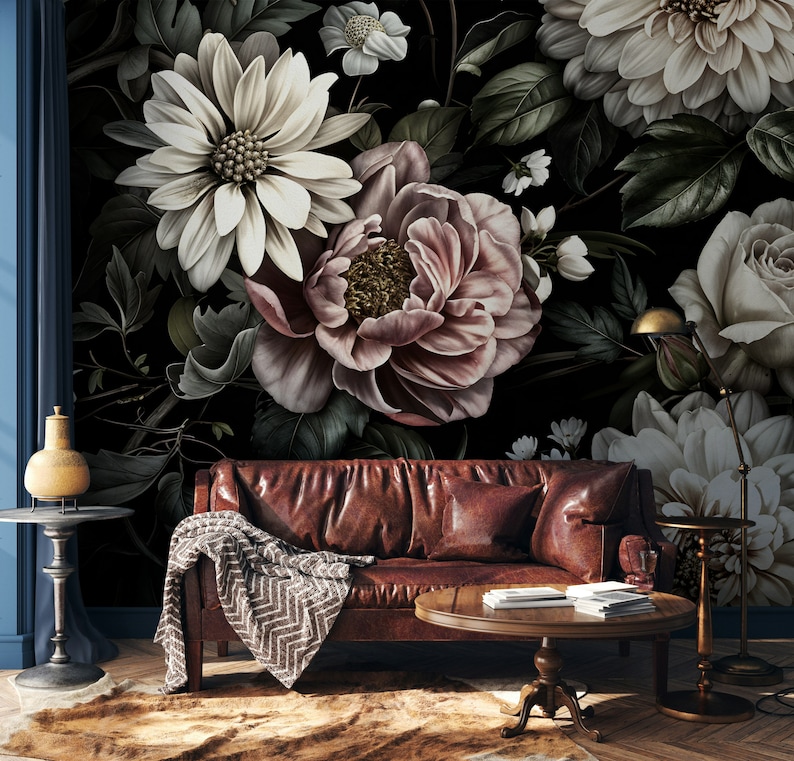 Puede incluir: Un sof&aacute; de cuero marr&oacute;n oscuro con una manta y una mesa de caf&eacute; delante. La pared detr&aacute;s del sof&aacute; est&aacute; cubierta con un papel tapiz floral con grandes flores blancas y rosas.