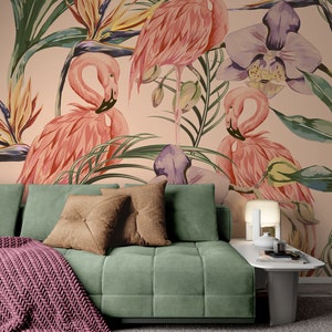 May include: A green velvet sofa with two brown throw pillows and a pink knitted throw blanket. The sofa is in front of a wall with a tropical wallpaper featuring pink flamingos, green leaves, and purple orchids.