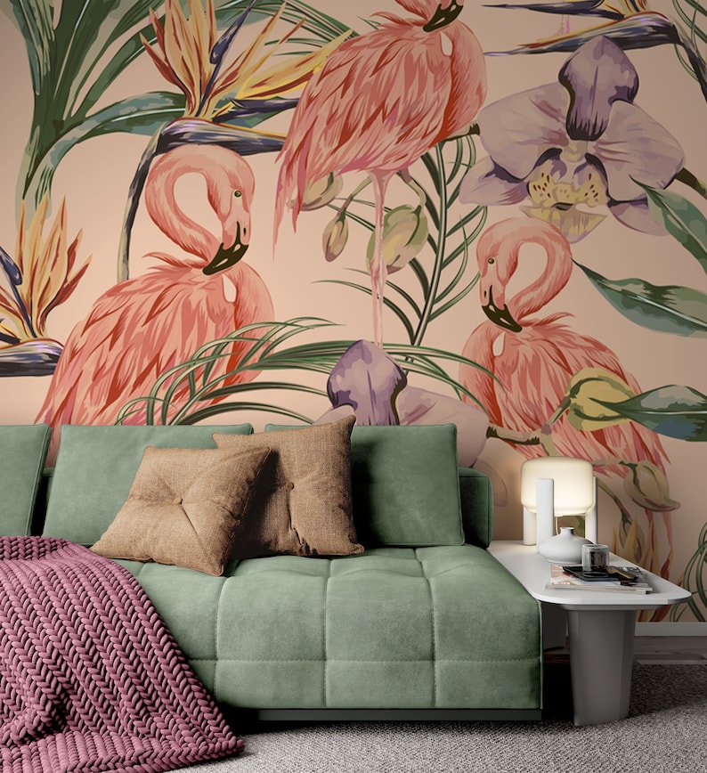 May include: A green velvet sofa with two brown throw pillows and a pink knitted throw blanket. The sofa is in front of a wall with a tropical wallpaper featuring pink flamingos, green leaves, and purple orchids.
