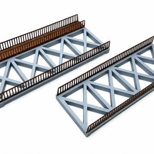 Può includere: Due sezioni di ponte in miniatura con una struttura a traliccio grigio chiaro e un motivo a X ripetuto. Ogni segmento del ponte è dotato di ringhiere marrone scuro su entrambi i lati, composte da listelli verticali e una barra orizzontale.
