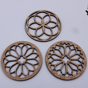 May include: Three laser-cut wooden coasters with intricate, circular designs. The coasters are light brown and feature various patterns, including floral and geometric shapes. The Feisbenn logo is in the upper right corner.