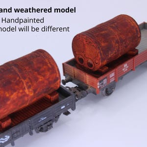 May include: Two model train flatcars, each carrying a large, cylindrical, rusted and weathered tank. The text on the image reads: Rusted and weathered model, Handpainted, Every model will be different. The flatcars are dark gray with red sides.