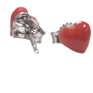 May include: A pair of silver heart-shaped earrings with red coral insets.