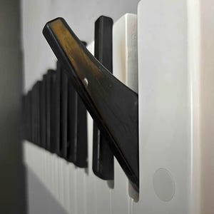 Könnte beinhalten: Nahaufnahme eines schwarz-weißen Klaviers mit einer einzigen schwarzen Taste, die heruntergedrückt ist. Die Taste ist aus dunklem Holzmaterial.