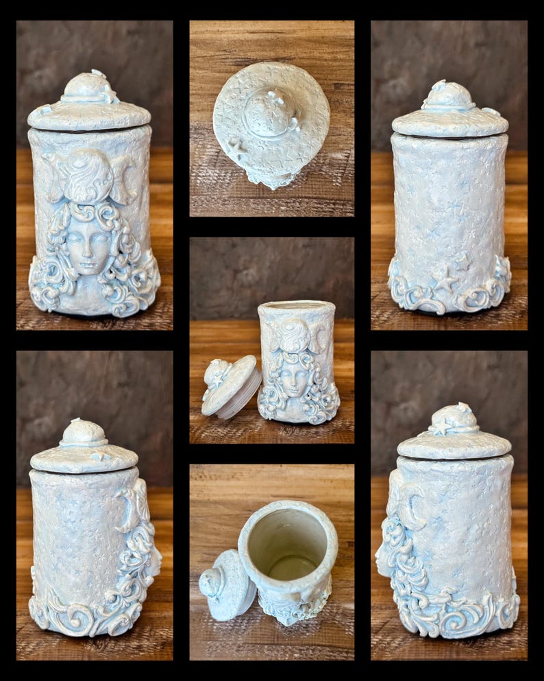 Peut inclure: Un pot cylindrique en c&eacute;ramique avec une finition bleu p&acirc;le textur&eacute;e et un couvercle assorti. L'ext&eacute;rieur pr&eacute;sente un relief sculpt&eacute; repr&eacute;sentant un visage aux cheveux fluides, des croissants de lune et de petites &eacute;toiles.
