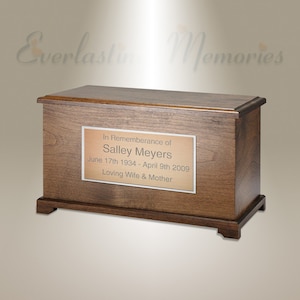 Pode incluir: Uma urna de cremação de madeira com uma placa de latão que diz "Em memória de Salley Meyers 17 de junho de 1934 - 9 de abril de 2009 Amada esposa e mãe"