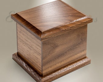 Peut inclure: Une petite boîte carrée en bois avec une finition brun foncé. La boîte a un design simple avec un couvercle légèrement surélevé et une base avec un léger rebord.
