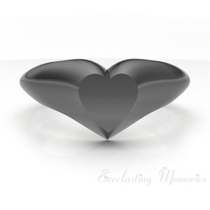 May include: A black ring with a heart-shaped cutout in the center. The ring is made of a smooth, shiny metal.