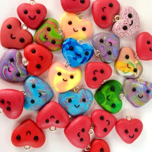 May include: A collection of colorful heart-shaped ornaments with painted faces. The hearts are made of clay and have a variety of patterns and colors, including blue, green, red, yellow, and purple.