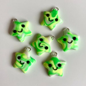 May include: Six green and white star-shaped charms with a smiley face on each. The charms are made of polymer clay and have a marbled effect.