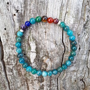 Peut inclure: Un bracelet de perles colorées avec un éventail de couleurs, dont le violet, le bleu, le vert, l'orange et le rouge. Le bracelet est composé de perles rondes et polies, enfilées sur un élastique. Les perles mesurent environ 0,8 cm de diamètre.