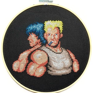 May include: Cross-stitch embroidery of two men, one with blue hair and the other with blonde hair, against a black background. The man with blue hair is wearing a red shirt and the man with blonde hair is wearing a white tank top.