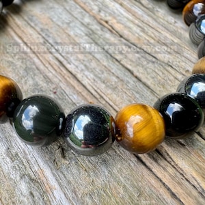 May include: A beaded bracelet featuring alternating polished spherical beads in tiger's eye with golden-brown chatoyancy and smooth, reflective black obsidian. The beads are strung together in a circular pattern, displaying a high-gloss finish.