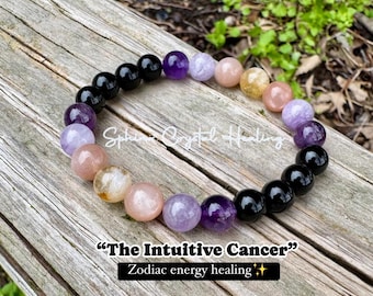May include: A beaded bracelet featuring a sequence of polished spherical stones in shades of black, deep purple, light lavender, peach, and translucent yellow. The text "The Intuitive Cancer" and "Zodiac energy healing" is overlaid on the image.