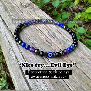 May include: Ankle bracelet with black, blue, purple, and silver beads. The bracelet features an evil eye charm and text that reads "Nice try... Evil Eye" and "Protection & third eye awareness anklet."