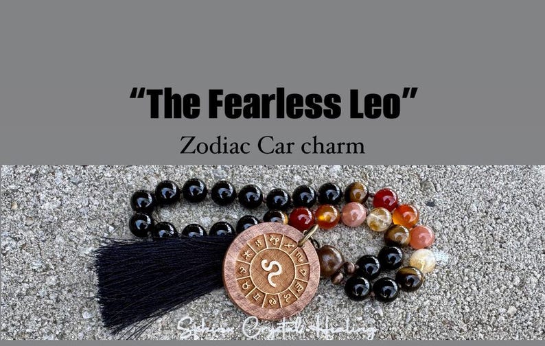 Puede incluir: Un abalorio de coche con borla negra que presenta un c&iacute;rculo de madera con el s&iacute;mbolo del zod&iacute;aco Leo y las palabras "The Fearless Leo" y "Zodiac Car charm".
